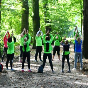 Een groep van ca. 15 Slow Sports trainers bezig met een oefening, in een bos.